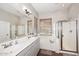 Well-lit bathroom with dual sinks, large mirror, tub, and a separate glass-enclosed shower at 35707 N 34Th Ln, Phoenix, AZ 85086