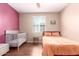 A bedroom features a dark accent wall, wood floors, plus a bed and crib at 4752 E Portola Valley Dr # 103, Gilbert, AZ 85297