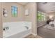 Well-lit bathroom showcasing soaking tub next to a window and an entrance to the main bedroom at 5423 W Yearling Rd, Phoenix, AZ 85083