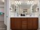 Double vanity bathroom featuring a warm wood cabinet, bright lighting, and modern mirrors at 5423 W Yearling Rd, Phoenix, AZ 85083