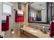 Well-lit bathroom with granite countertops, decorative mirror, and red accent towels at 5751 E Ludlow Dr, Scottsdale, AZ 85254