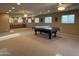 Spacious carpeted recreation room featuring a ping pong table, multiple ceiling fans, and ample natural light from the windows at 5751 E Ludlow Dr, Scottsdale, AZ 85254