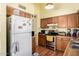 Kitchen featuring wood cabinets, appliances, and a refrigerator adorned with photos and notes at 7302 W Meadowbrook Ave, Phoenix, AZ 85033