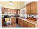A kitchen featuring wood cabinets, stainless steel appliances, and a window with blinds at 7302 W Meadowbrook Ave, Phoenix, AZ 85033