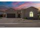 Charming single-story home featuring a stone facade, arched entryway, and spacious driveway, all set against a vibrant sunset sky at 8021 E Jasmine St, Mesa, AZ 85207