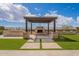 Relaxing outdoor fireplace with stone accents, a pergola, and surrounded by lush green lawn at 8021 E Jasmine St, Mesa, AZ 85207