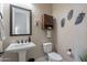 Elegant powder room with pedestal sink, decorative accents, and a convenient wall-mounted cabinet at 8021 E Jasmine St, Mesa, AZ 85207