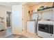 This laundry room has tile flooring, a washer, a dryer, and shelves at 8043 W Albeniz Pl, Phoenix, AZ 85043