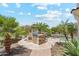 Outdoor kitchen featuring a built-in grill and bar seating, surrounded by palm trees and lush landscaping at 8540 E Mcdowell Rd # 10, Mesa, AZ 85207