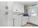 Laundry room featuring front load washer and dryer, ample cabinet space, and exterior door at 8714 E Mackenzie Dr, Scottsdale, AZ 85251