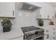 Modern kitchen featuring stainless steel stove, range hood, and white cabinetry at 8941 E Maple Dr, Scottsdale, AZ 85255