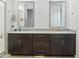 Bathroom includes double sinks, dark wood cabinets, and tiled shower with glass doors at 9310 W Atlantis Way, Tolleson, AZ 85353