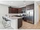 Modern kitchen with stainless steel appliances, dark cabinets, and a breakfast bar at 9310 W Atlantis Way, Tolleson, AZ 85353