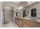 Bathroom featuring a double vanity, neutral tiling, and ample lighting, with a view to walk-in closet and shower at 11360 E Keats Ave # 70, Mesa, AZ 85209