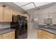 Spacious kitchen boasting wooden cabinetry, black appliances, granite countertops, and tiled flooring at 11360 E Keats Ave # 70, Mesa, AZ 85209