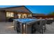 Outdoor patio at dusk featuring a hot tub with bar, surrounded by comfortable seating and ambient lighting at 12269 E Chiricahua Pl, Gold Canyon, AZ 85118
