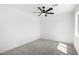 Clean, minimalist bedroom with carpet, ceiling fan, and natural light from a window at 12506 W Corrine Dr, El Mirage, AZ 85335
