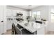 Modern white kitchen with stainless appliances, quartz counters, and stylish barstool seating at 12506 W Corrine Dr, El Mirage, AZ 85335