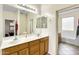 Bathroom featuring double sinks, wood cabinets and a view of the walk-in shower and soaking tub at 15339 W Jefferson St, Goodyear, AZ 85338
