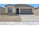 Charming single-story home with a gray door, two-car garage, and low-maintenance desert landscaping at 18052 W Sand Hills Rd, Surprise, AZ 85387