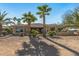 Lovely home exterior with desert landscaping and manicured bushes and palm trees, in the backyard at 19714 N Rim Dr, Surprise, AZ 85374