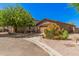 View of the single-story home with desert landscaping, mature trees, and a two car garage at 2024 E Dust Devil Dr, San Tan Valley, AZ 85143