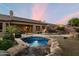 Lush backyard featuring a tranquil pool with rock features, a spacious patio, and beautiful green landscaping at 22231 N 55Th St, Phoenix, AZ 85054