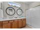 A bathroom featuring dual sinks, a large mirror, and a glass-enclosed shower at 22815 N Arrellaga Dr, Sun City West, AZ 85375