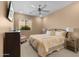 Cozy bedroom with a large window, ceiling fan, dresser, and comfortable bed with decorative pillows at 2304 N Steele Cir, Mesa, AZ 85207