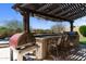Outdoor kitchen featuring a pizza oven, built-in grill, bar seating under a pergola with string lights at 2304 N Steele Cir, Mesa, AZ 85207