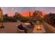 Expansive backyard patio featuring firepit, lounge chairs, manicured lawn, and colorful sunset at 29706 N 127Th Ln, Peoria, AZ 85383
