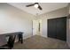 Carpeted bedroom featuring a black desk, a ceiling fan, and a closet with bi-fold doors at 29706 N 127Th Ln, Peoria, AZ 85383