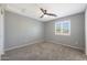 Bedroom with neutral tones and carpet, featuring a ceiling fan and shuttered window at 29706 N 127Th Ln, Peoria, AZ 85383