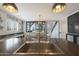Open-concept kitchen featuring a sink in island and view into the adjacent dining and living areas at 29706 N 127Th Ln, Peoria, AZ 85383