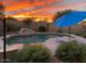 Backyard pool featuring rock waterfall, desert landscaping, sun umbrella, and stunning sunset views at 29706 N 127Th Ln, Peoria, AZ 85383