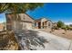 Single-story home with a two-car garage, extended driveway, and desert landscaping in the front yard at 30208 W Fairmount Ave, Buckeye, AZ 85396