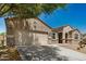Tan-colored single-story home with a two-car garage, desert landscaping, and a long driveway at 30208 W Fairmount Ave, Buckeye, AZ 85396