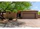 Tan home with a tile roof, gravel landscaping, and a green desert tree in front at 32627 N 70Th St, Scottsdale, AZ 85266