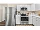 Updated kitchen with stainless steel appliances, white cabinets, and solid surface countertops at 3365 W Thude Dr, Chandler, AZ 85226