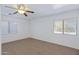 Bright bedroom with neutral carpet, two windows, and modern ceiling fan fixture at 43232 W Magnolia Rd, Maricopa, AZ 85138