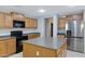 Bright kitchen featuring wooden cabinets, gray countertops, a center island, and stainless steel refrigerator at 43232 W Magnolia Rd, Maricopa, AZ 85138