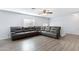 Spacious living area features modern wood-look floors and a large sectional sofa at 43232 W Magnolia Rd, Maricopa, AZ 85138