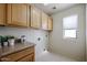 Bright laundry room with upper cabinets, neutral walls and white tile flooring at 5323 E Hopi Ave, Mesa, AZ 85206