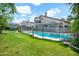 Spacious backyard featuring a pool with a black fence, large grassy area, and mature trees at 5406 E Charleston Ave, Scottsdale, AZ 85254