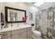 Bright bathroom with large vanity mirror, vanity, and shower with patterned curtain at 5528 E Virginia Ave, Phoenix, AZ 85008