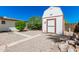 Backyard view of a storage shed with a red trim, surrounded by low-maintenance gravel and some plants at 5625 E Dodge St, Mesa, AZ 85205