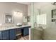 Bathroom featuring double sinks, blue cabinetry, granite countertops, and a walk-in shower with glass and tile surround at 6128 E Portia St, Mesa, AZ 85215