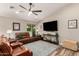 Comfortable living room featuring a ceiling fan, a large television, and a plush brown leather sofa at 6128 E Portia St, Mesa, AZ 85215