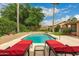 Sparkling pool with red lounge chairs, lush landscaping, and a refreshing outdoor oasis for enjoying sunny days at 6128 E Portia St, Mesa, AZ 85215