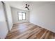 Bright bedroom featuring wood-look flooring, white walls, ceiling fan, and a large window at 6228 E Blanche Dr, Scottsdale, AZ 85254